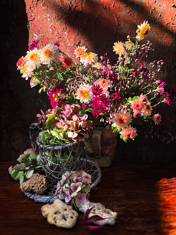 Home decor and flowers arranging. Autumn bouquet with chrysanthemums flowers and dry hydrangea flowers in the rays of sunlight on an old rusty background