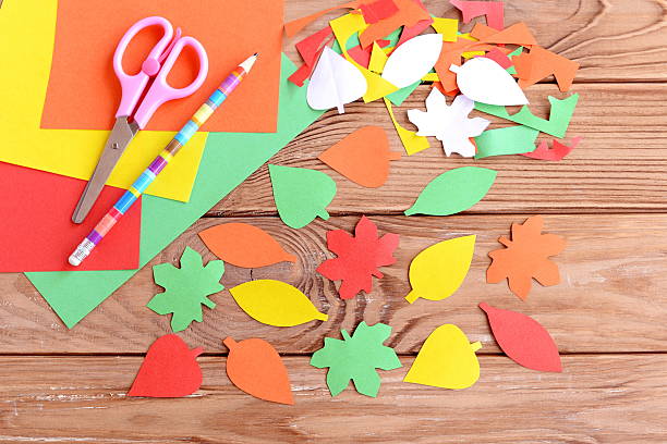 Autumn colored paper leaves on wooden background stock photo