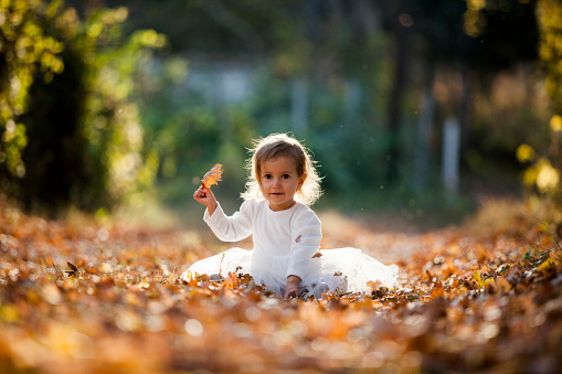cute little girl sitting outdoor in white dress