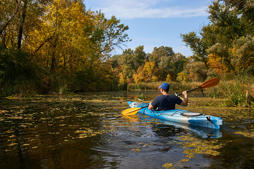 Man kayaking on lake in autumn. Active tourism.