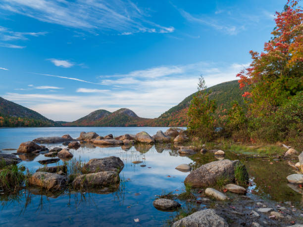 Autumn scene  of tree-covered hills surrounding pond with rocks stock photo