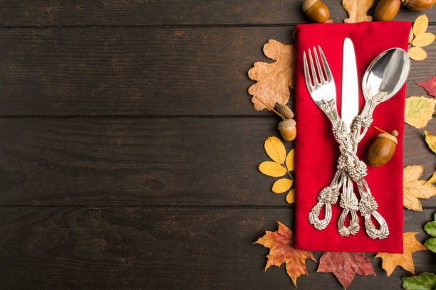 Autumn thanksgiving table with tableware and red tissue Autumn thanksgiving table with tableware and red tissue over wooden table, flat lay style with copy space thanksgiving diner stock pictures, royalty-free photos & images