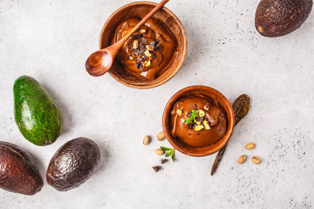 Avocado chocolate mousse with pistachios in wooden bowl on white background. stock photo