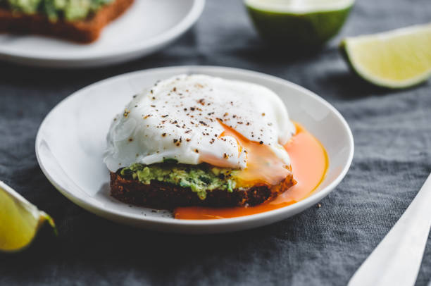 Avocado sandwich with rye bread and a poached egg on a plate. The concept of healthy balanced breakfast. Avocado sandwich with a poached egg on a plate. The concept of healthy balanced breakfast. poached food photos stock pictures, royalty-free photos & images