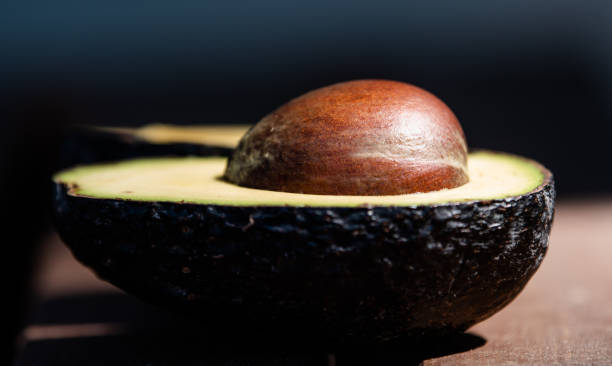 Avocado sliced in half Cut open avocado with bright pit michelle tresemer stock pictures, royalty-free photos & images