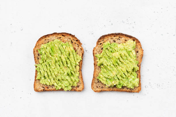 Avocado toast on whole grain sandwich bread Avocado toast on whole grain sandwich bread. Table top view. Mashed avocado toasts. Concept of healthy eating, dieting, vegan vegetarian food toasted bread stock pictures, royalty-free photos & images