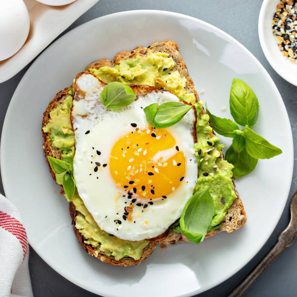 Avocado toast with fried egg Avocado toast with fried sunny side up egg overhead view poached food photos stock pictures, royalty-free photos & images