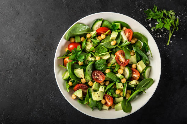 Avocado, tomato, chickpeas, spinach and cucumber salad Avocado, tomato, chickpeas, spinach and cucumber salad. Top view chick pea stock pictures, royalty-free photos & images