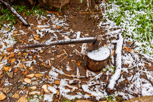 A axe stuck in a piece of wood in snow