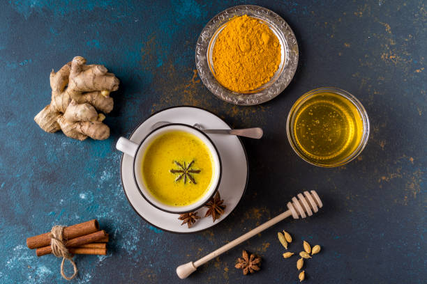 Ayurvedic golden turmeric latte milk made with turmeric and other spiceson blue background. Flat lay. stock photo