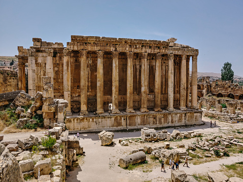 The Baalbeck Temple surrounded by trees and people under the sunlight at daytime in Lebanon. Vacation places concept
