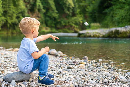 baby boy alone throwing a stone on river