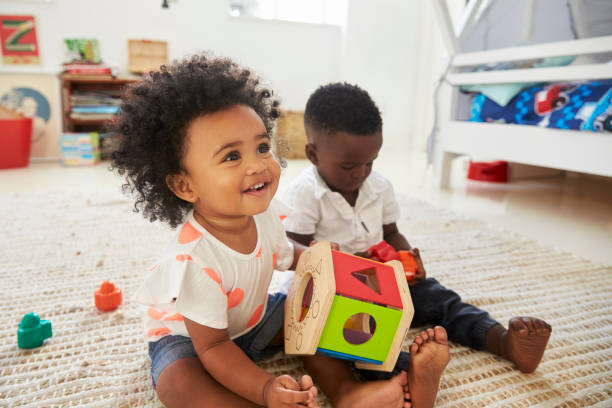 baby boy and girl playing with toys in playroom together - criança pequena imagens e fotografias de stock