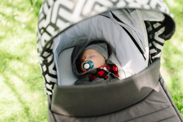 Baby boy in jacket and hat sleeping in modern stroller on a walk in a park. Child in buggy. Close Up of stroller with newborn. Top view. stock photo