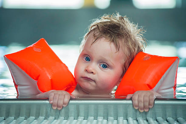 Baby boy makes face in a swiming pool stock photo