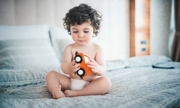 Baby boy playing on bed. stock photo