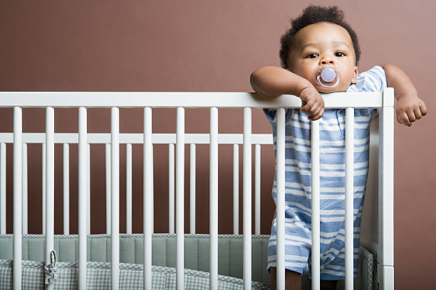 baby boy standing in cot - cradle to cradle stockfoto's en -beelden