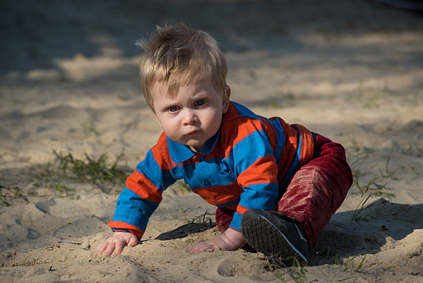 Baby boy with hearing aid in sandbox stock photo
