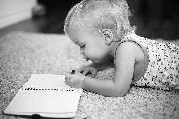 Baby boy writing in a notebook stock photo