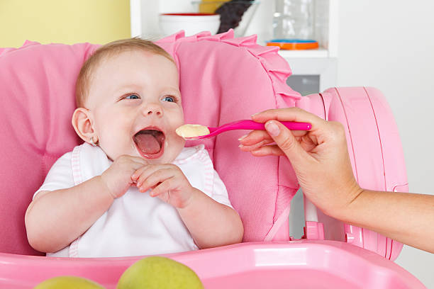 Baby eating in the high chair stock photo