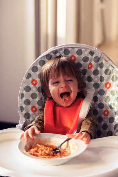 Baby eats spaghetti and grins stock photo