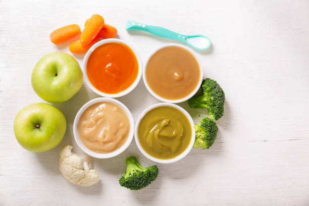 Baby food. Various kinds of bowls of fruit and vegetable puree with fresh fruits and vegetables stock photo