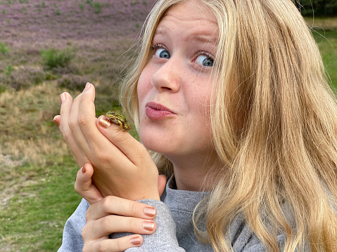 Teenage girl meets a baby frog n the heath area cold Brunssummerheide