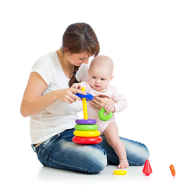 baby girl and mother playing together with toy stock photo