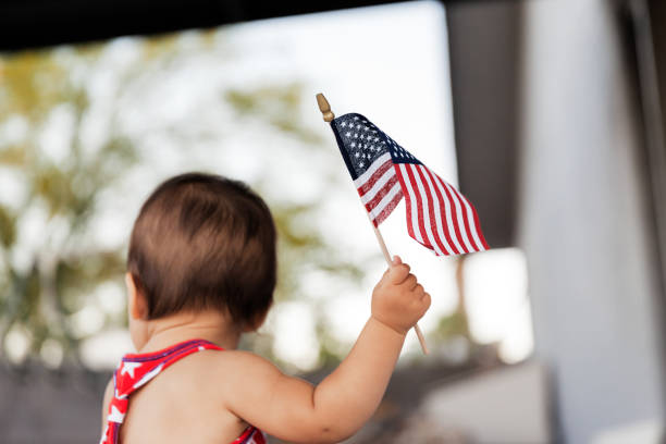 Baby girl celebrating  4th of July with USA flag in hand, Traditional American Holiday stock photo