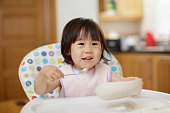 女の赤ちゃんは、家庭の台所でヨーグルトを食べる
