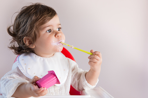 Baby Girl Eating Yogurt With Messy Face Stock Photo ...