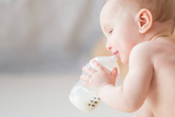 dziewczynka trzymająca butelkę mleka rano. czas karmienia. zbliżenie. - baby formula zdjęcia i obrazy z banku zdjęć
