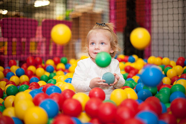 Baby girl in ball pool Baby girl in ball pool indoor playground stock pictures, royalty-free photos & images