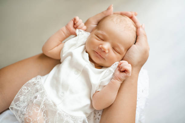 Baby girl on mother hands in room closeup stock photo