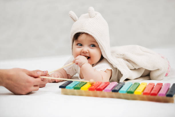 Baby girl playing with xylophone toy on blanket at home stock photo