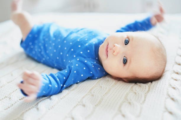 Baby girl wearing blue clothes relaxing in bedroom stock photo