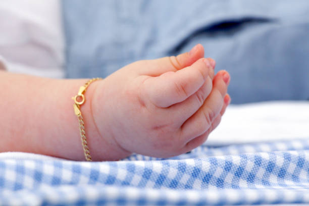 Baby hand with gold bracelet stock photo