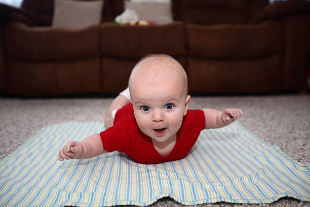 Baby having tummy time with his hands like flying stock photo