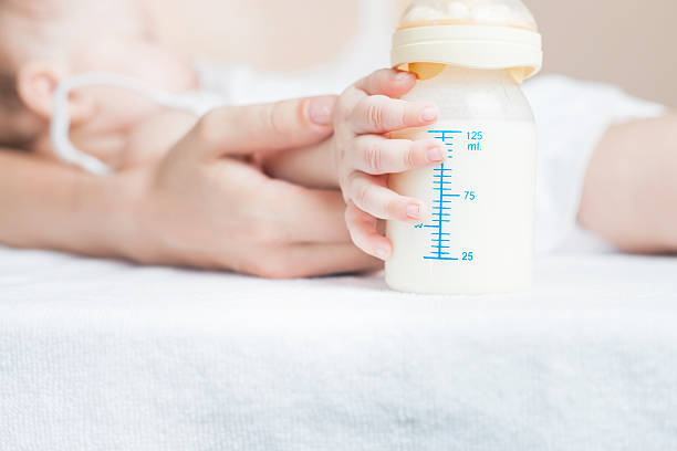 baby holding a baby bottle with breast milk - baby formula 個照片及圖片檔