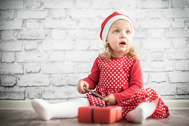 Baby in Santa's hat with Christmas present - smartphone stock photo