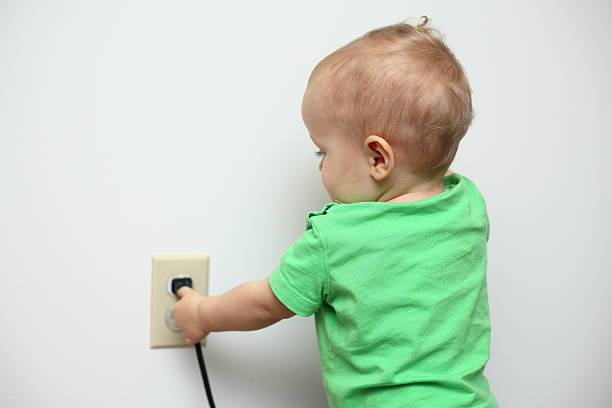 Baby playing with a power cord stock photo