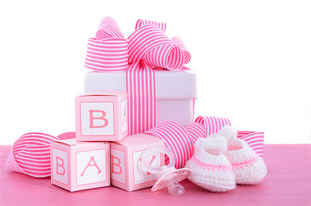 Baby shower Its a Girl pink gift Baby shower Its a Girl pink gift with baby booties, dummy and gift box on pink shabby chic wood table. it's a girl stock pictures, royalty-free photos & images