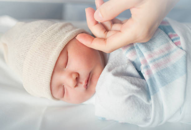 Baby sleeping Mothers hand comforting new born baby boy sleeping. blanket photos stock pictures, royalty-free photos & images