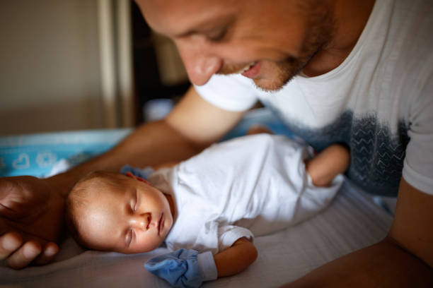 baby slapen terwijl vader hem beschermen - wiegman stockfoto's en -beelden