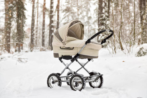 Baby stroller in winter forest. tire tracks on snow. Infant baby sleep inside the pram on fresh air stock photo