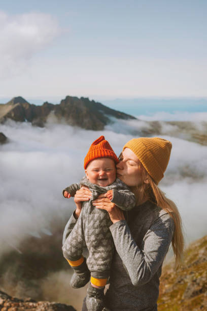 Baby with mother traveling hiking family vacation outdoor active vacations woman mom with daughter kid enjoying mountains view healthy lifestyle tour in Norway stock photo