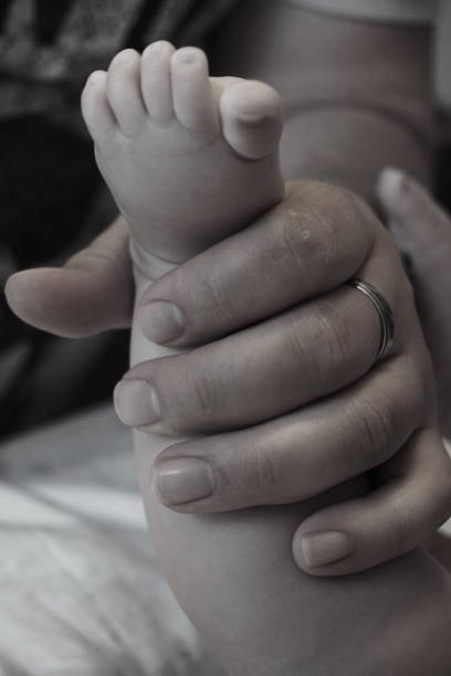 Baby's foot in father's hand stock photo