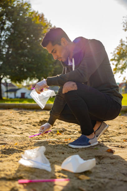 Back lit of male volunteer cleaning garbage on sand at park stock photo