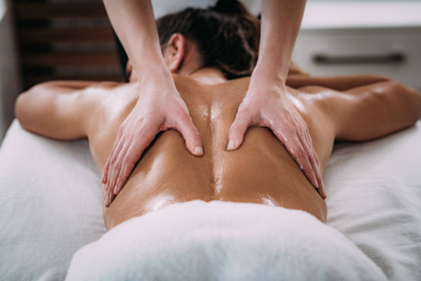 Back Sports Massage Therapy Physiotherapist massaging female patient with injured lower back muscle. Sports injury treatment. massage stock pictures, royalty-free photos & images