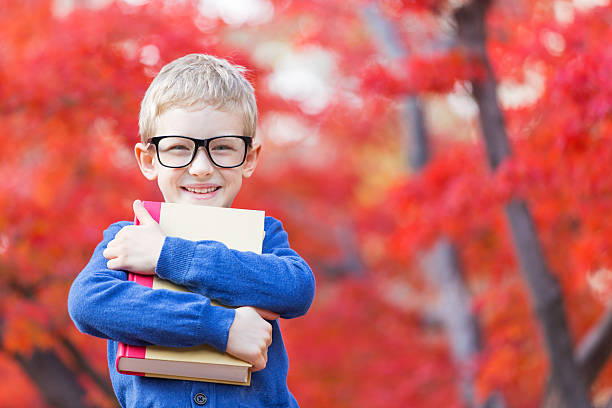 back to school portrait of smart little boy in glasses holding book ready for school in beautiful autumn park boys glasses stock pictures, royalty-free photos & images